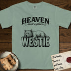 Heaven Isn't a Place Westie T-Shirt flat lay in Bay, featuring Black ink engraving illustration of a Westie asleep on top of the giant carved block letters WESTIE, under the lettering HEAVEN isn't a place..