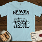 Heaven Isn't a Place Westie T-Shirt flat lay in Chambray, featuring Black ink engraving illustration of a Westie asleep on top of the giant carved block letters WESTIE, under the lettering HEAVEN isn't a place..