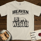 Heaven Isn't a Place Westie T-Shirt flat lay in Ivory, featuring Black ink engraving illustration of a Westie asleep on top of the giant carved block letters WESTIE, under the lettering HEAVEN isn't a place..