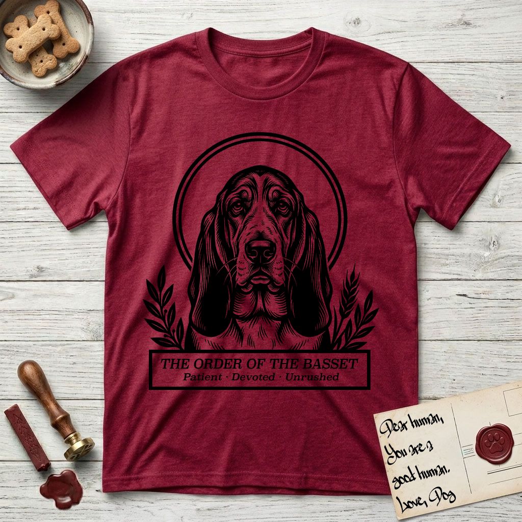 Holy Orders Basset Hound T-Shirt flat lay in Antique Cherry Red, featuring a bold black-and-white linocut saint-medallion portrait of a Basset Hound.