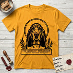 Holy Orders Basset Hound T-Shirt flat lay in Gold, featuring a bold black-and-white linocut saint-medallion portrait of a Basset Hound.