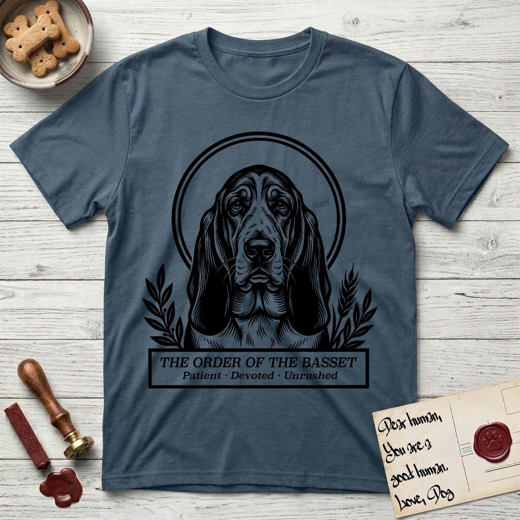 Holy Orders Basset Hound T-Shirt flat lay in Indigo Blue, featuring a bold black-and-white linocut saint-medallion portrait of a Basset Hound.