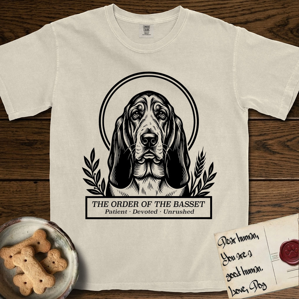Holy Orders Basset Hound T-Shirt flat lay in Ivory, featuring a bold black-and-white linocut saint-medallion portrait of a Basset Hound.