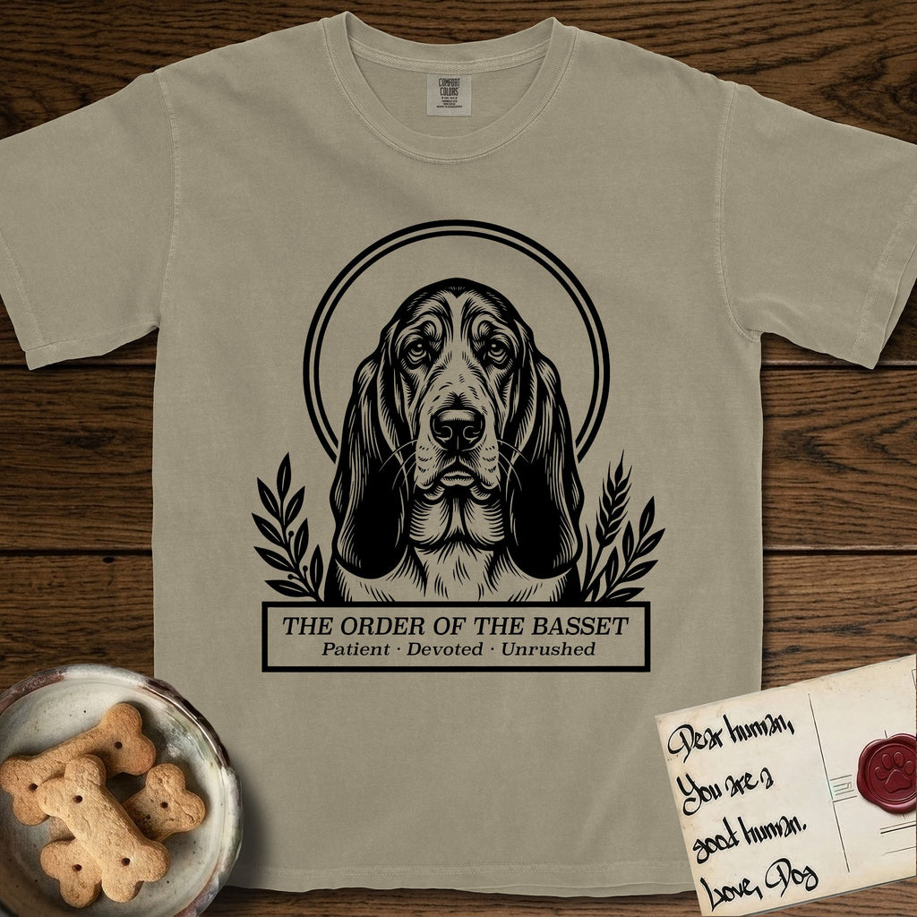Holy Orders Basset Hound T-Shirt flat lay in Khaki, featuring a bold black-and-white linocut saint-medallion portrait of a Basset Hound.
