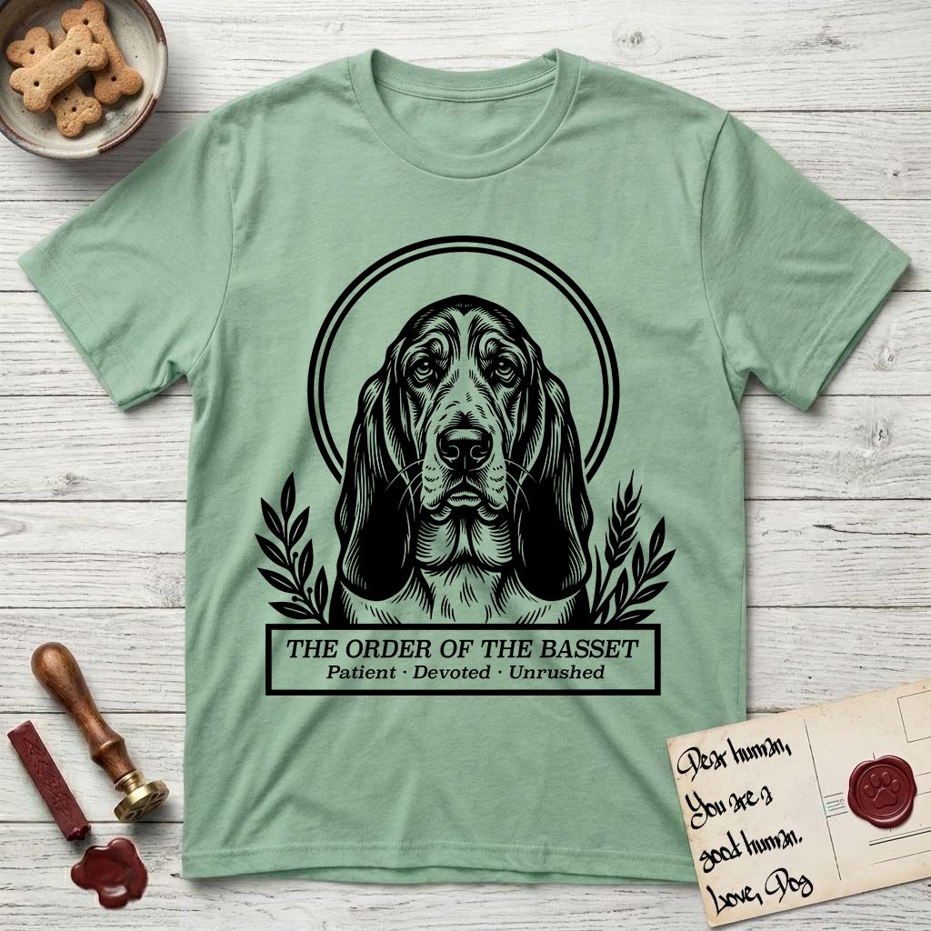 Holy Orders Basset Hound T-Shirt flat lay in Mint Green, featuring a bold black-and-white linocut saint-medallion portrait of a Basset Hound.