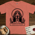 Holy Orders Basset Hound T-Shirt flat lay in Terracotta, featuring a bold black-and-white linocut saint-medallion portrait of a Basset Hound.