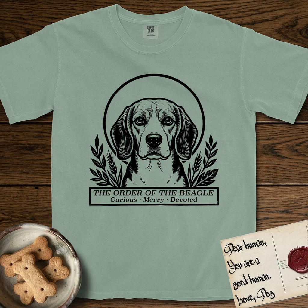 Holy Orders Beagle T-Shirt flat lay in Bay, featuring a bold black-and-white linocut saint-medallion portrait of a Beagle.