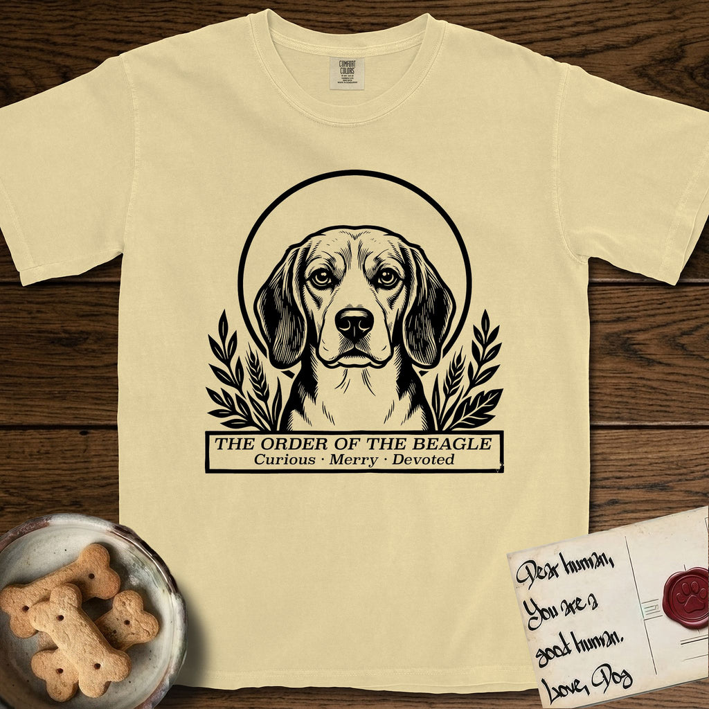 Holy Orders Beagle T-Shirt flat lay in Butter, featuring a bold black-and-white linocut saint-medallion portrait of a Beagle.