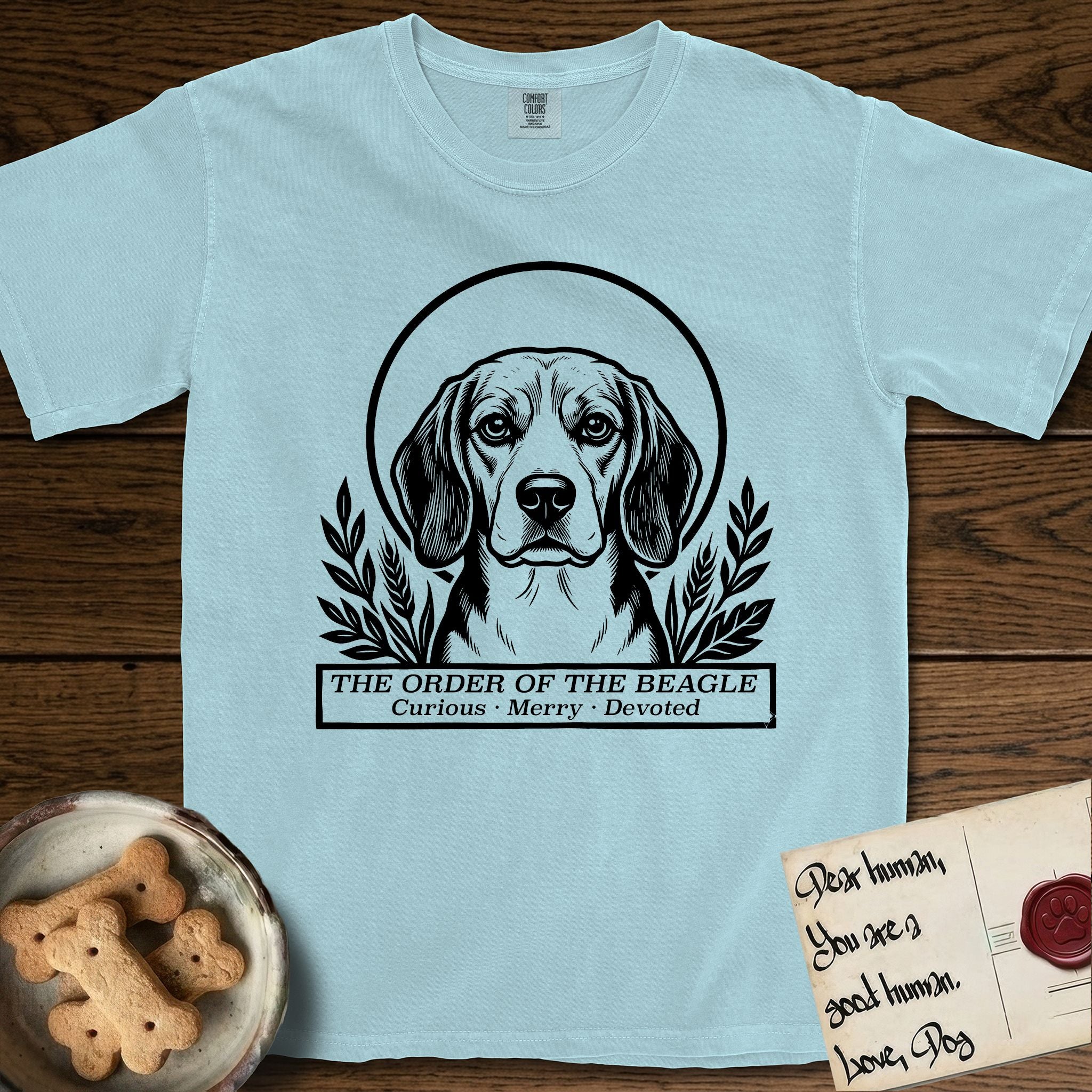 Holy Orders Beagle T-Shirt flat lay in Chambray, featuring a bold black-and-white linocut saint-medallion portrait of a Beagle.