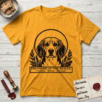 Holy Orders Beagle T-Shirt flat lay in Gold, featuring a bold black-and-white linocut saint-medallion portrait of a Beagle.