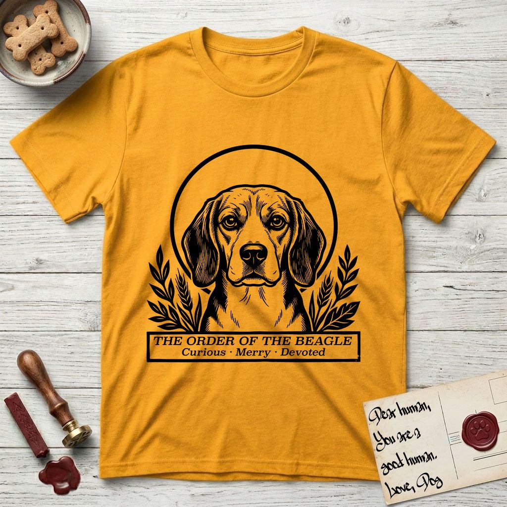Holy Orders Beagle T-Shirt flat lay in Gold, featuring a bold black-and-white linocut saint-medallion portrait of a Beagle.