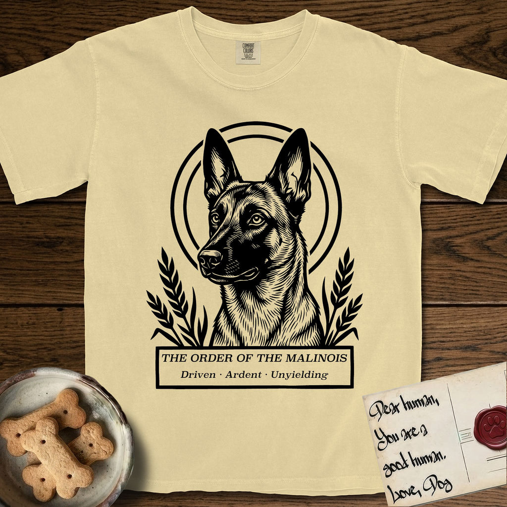 Holy Orders Belgian Malinois T-Shirt flat lay in Butter, featuring a bold black-and-white linocut saint-medallion portrait of a Belgian Malinois.
