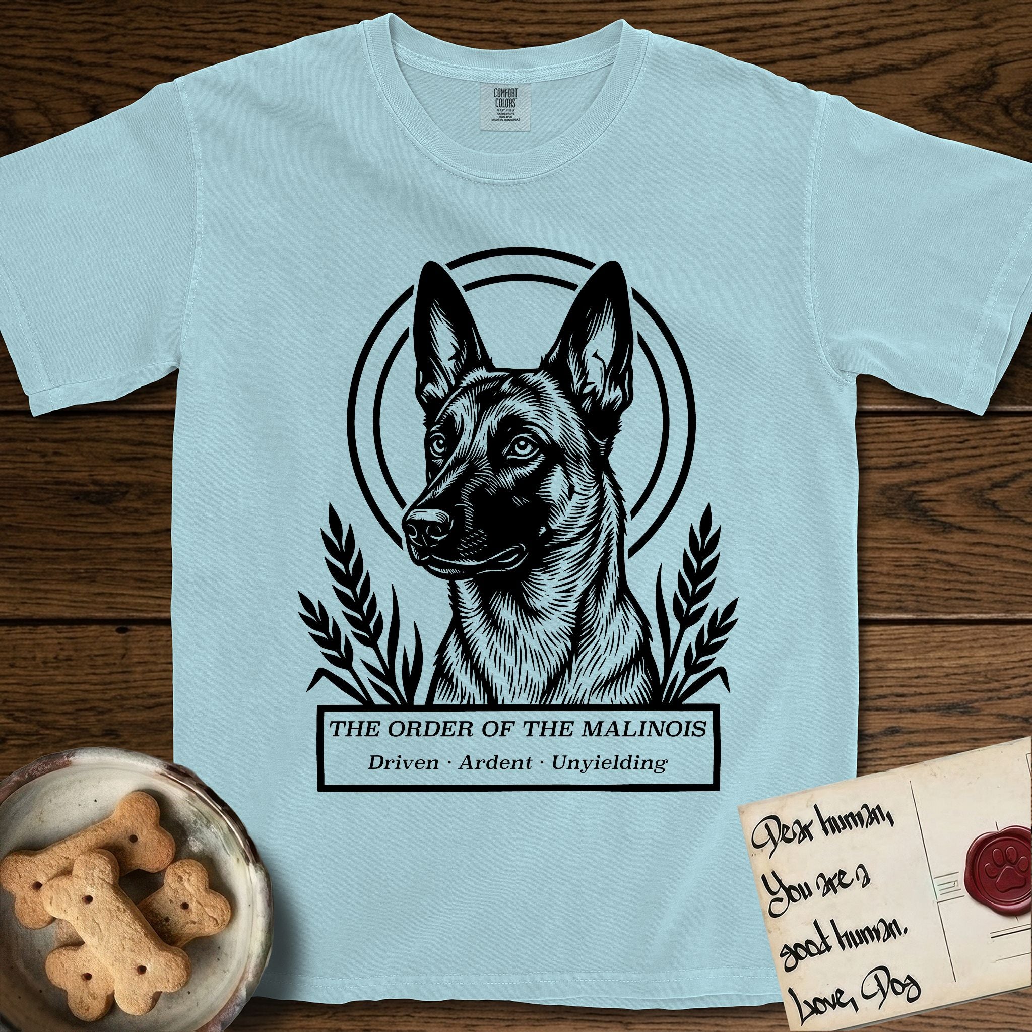 Holy Orders Belgian Malinois T-Shirt flat lay in Chambray, featuring a bold black-and-white linocut saint-medallion portrait of a Belgian Malinois.