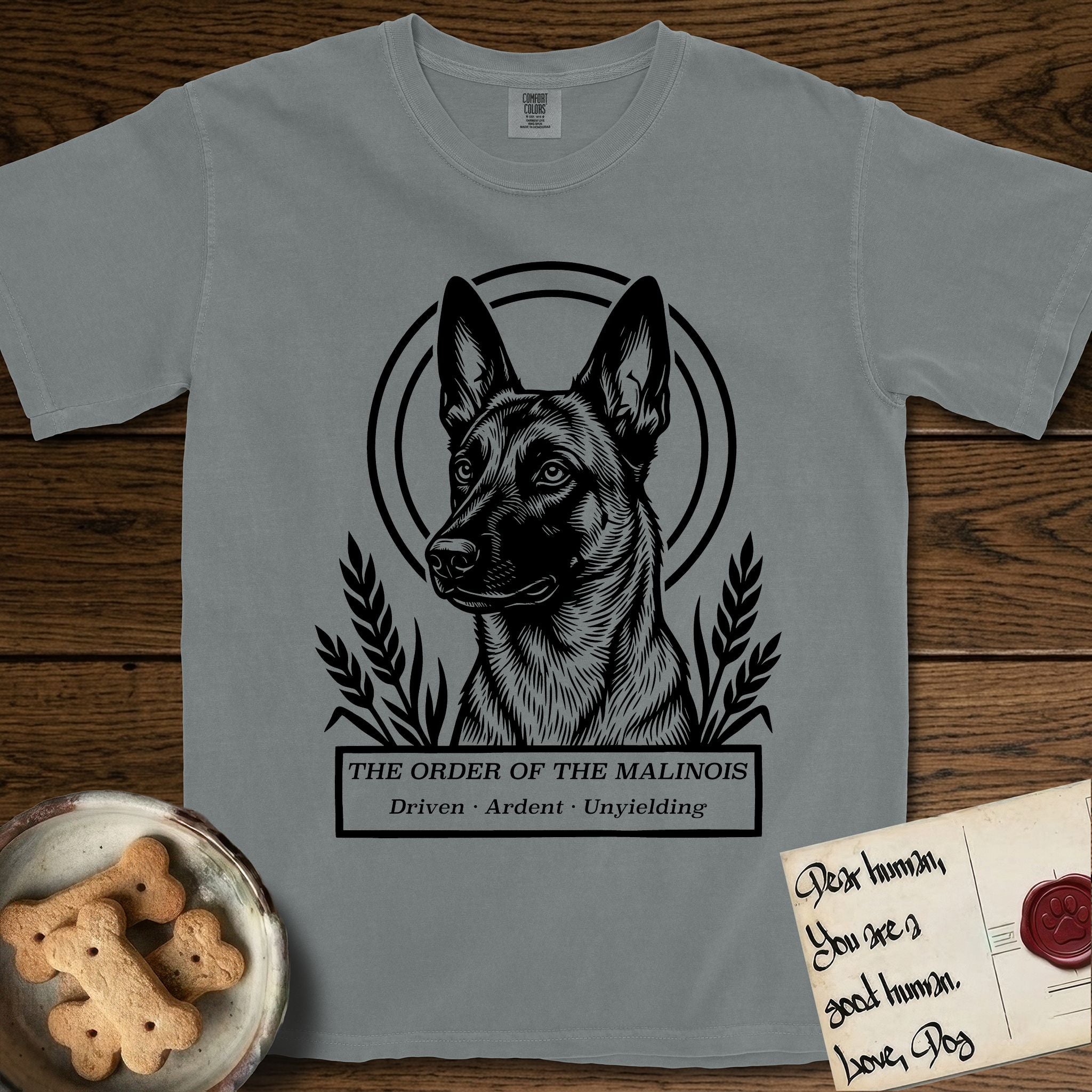 Holy Orders Belgian Malinois T-Shirt flat lay in Granite, featuring a bold black-and-white linocut saint-medallion portrait of a Belgian Malinois.