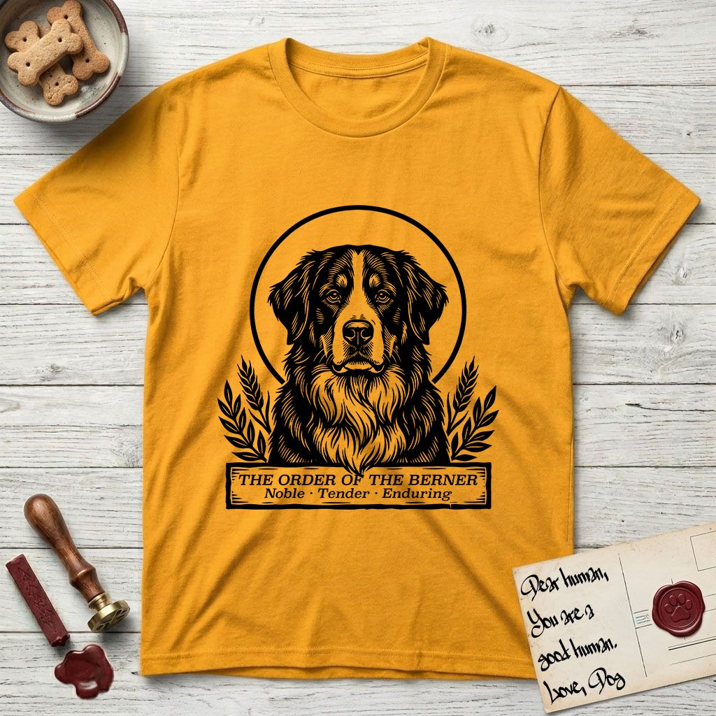 Holy Orders Bernese Mountain Dog T-Shirt flat lay in Gold, featuring a bold black-and-white linocut saint-medallion portrait of a Bernese Mountain Dog.