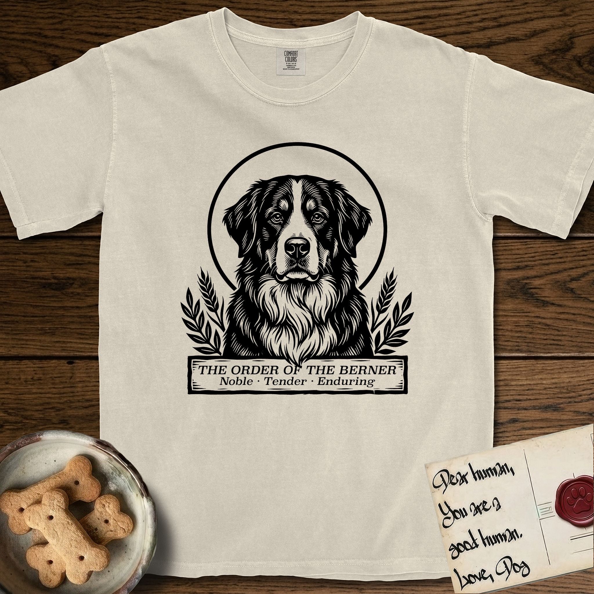 Holy Orders Bernese Mountain Dog T-Shirt flat lay in Ivory, featuring a bold black-and-white linocut saint-medallion portrait of a Bernese Mountain Dog.