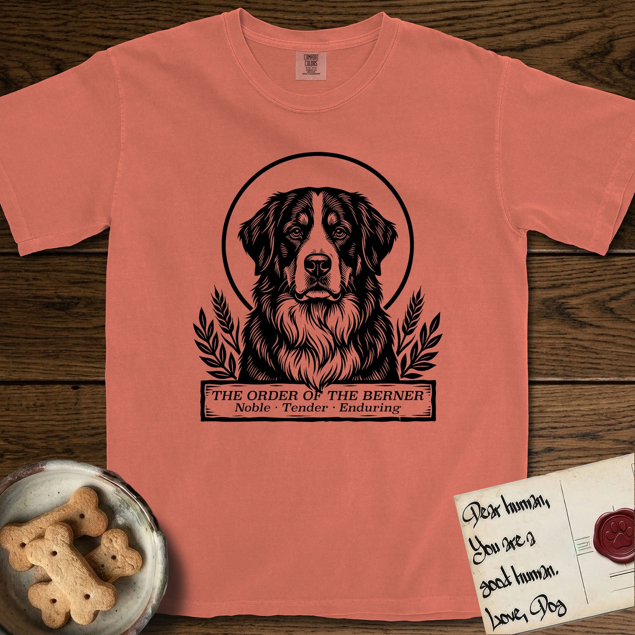 Holy Orders Bernese Mountain Dog T-Shirt flat lay in Terracotta, featuring a bold black-and-white linocut saint-medallion portrait of a Bernese Mountain Dog.