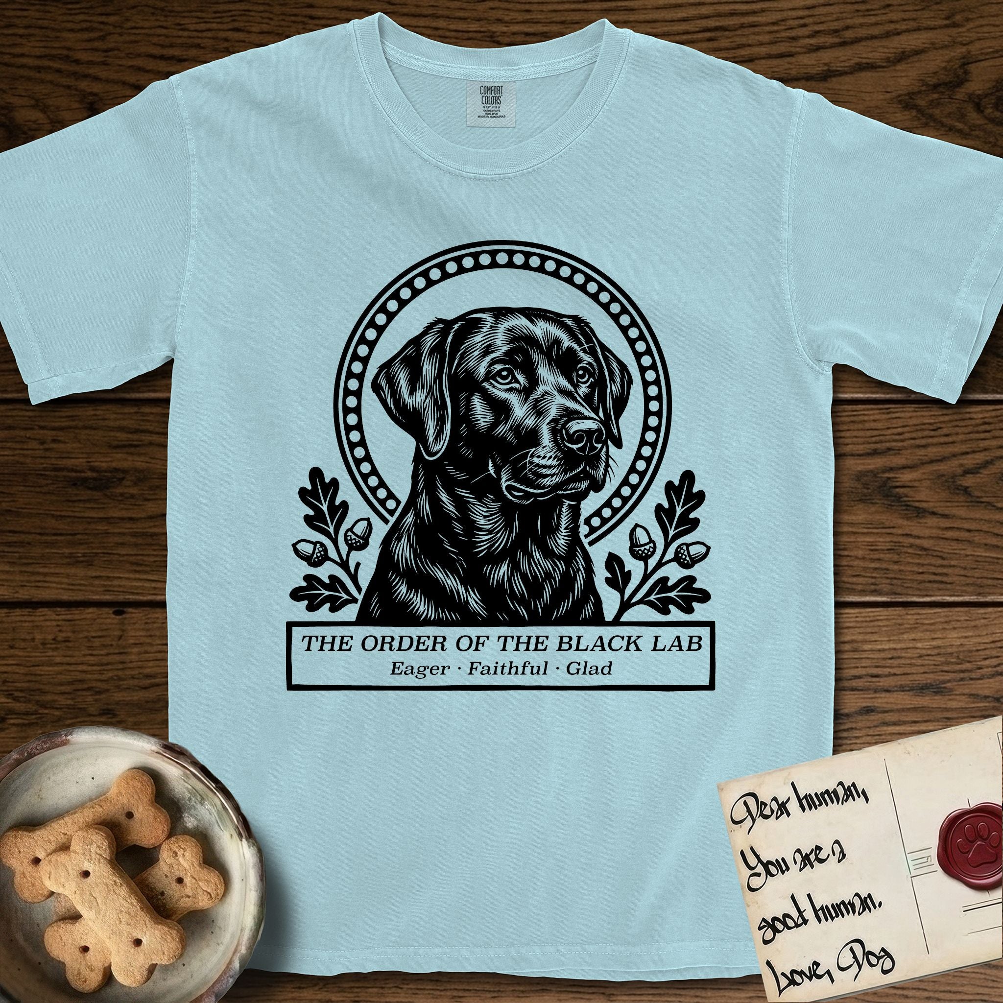 Holy Orders Black Lab T-Shirt flat lay in Chambray, featuring a bold black-and-white linocut saint-medallion portrait of a Black Lab.