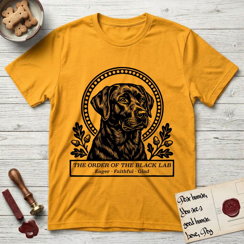 Holy Orders Black Lab T-Shirt flat lay in Gold, featuring a bold black-and-white linocut saint-medallion portrait of a Black Lab.