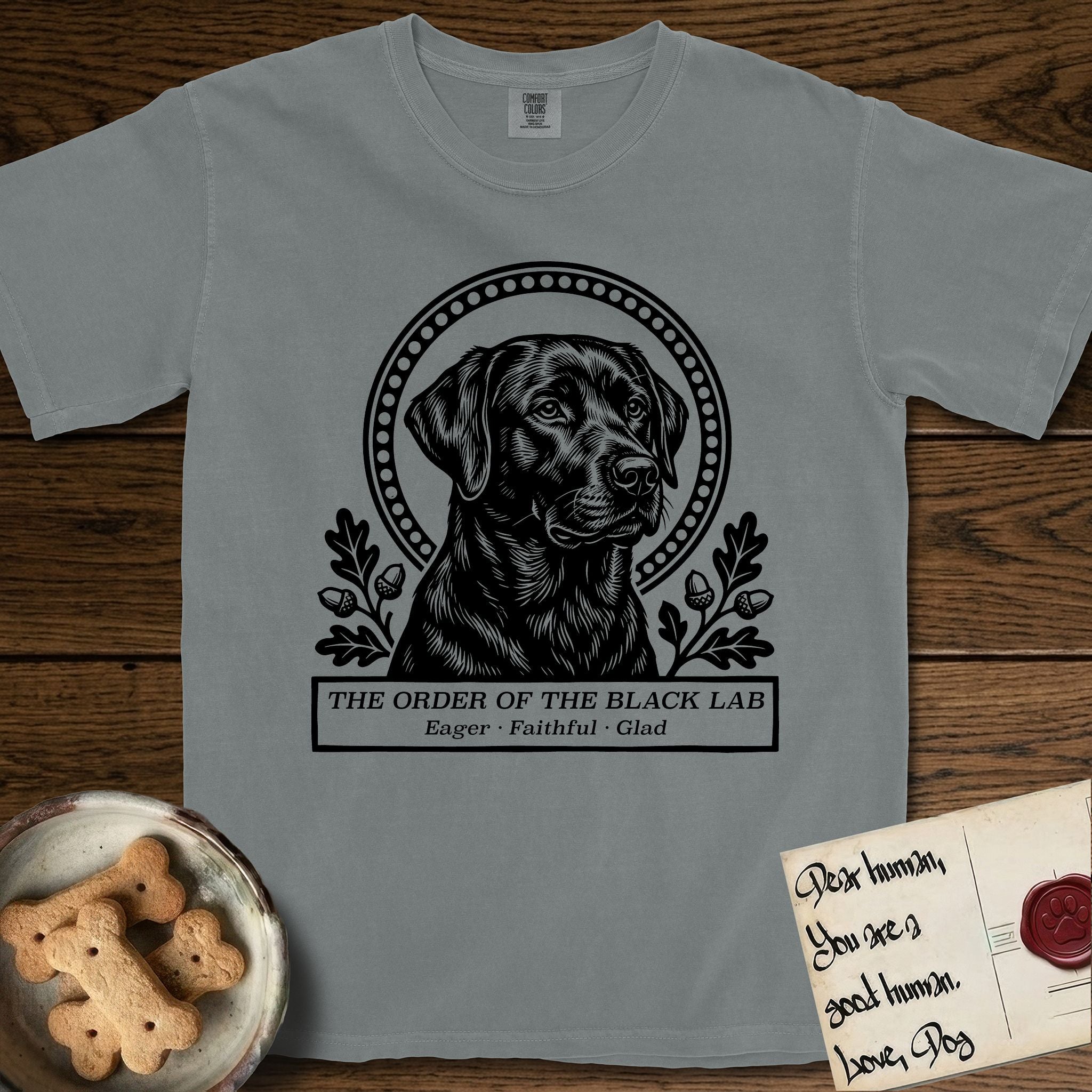 Holy Orders Black Lab T-Shirt flat lay in Granite, featuring a bold black-and-white linocut saint-medallion portrait of a Black Lab.