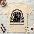 Holy Orders Black Lab T-Shirt flat lay in Natural, featuring a bold black-and-white linocut saint-medallion portrait of a Black Lab.