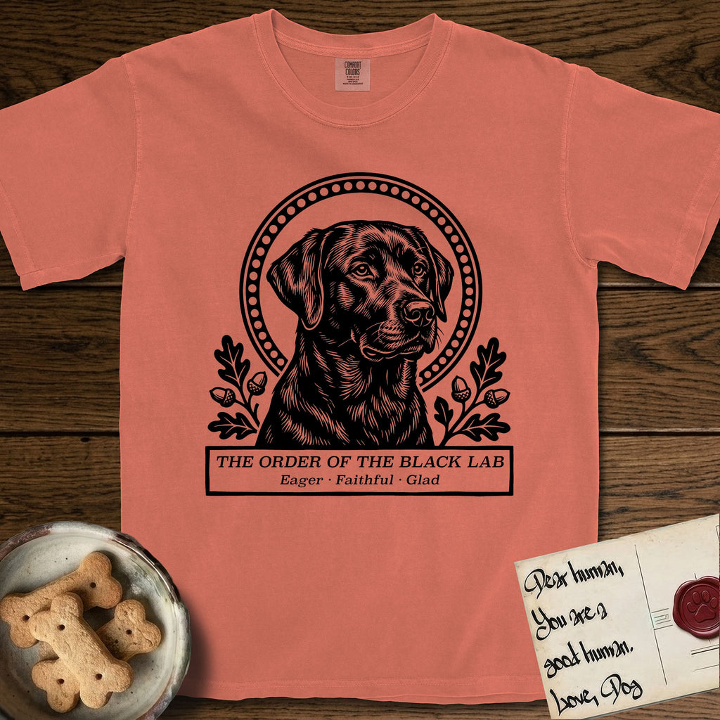 Holy Orders Black Lab T-Shirt flat lay in Terracotta, featuring a bold black-and-white linocut saint-medallion portrait of a Black Lab.