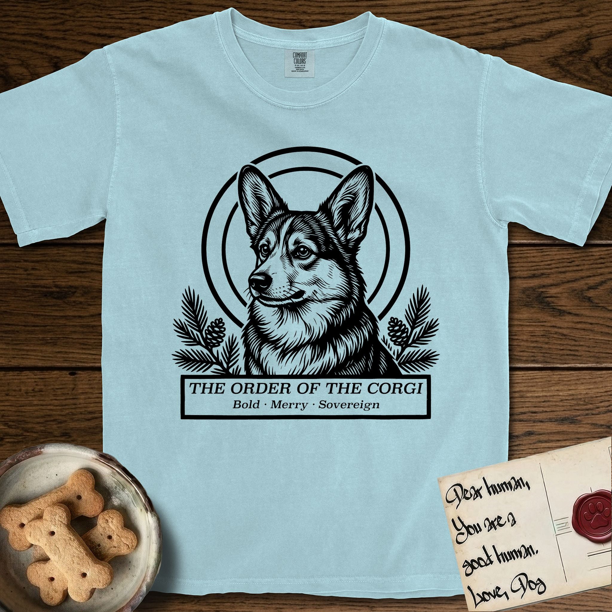 Holy Orders Corgi T-Shirt flat lay in Chambray, featuring a bold black-and-white linocut saint-medallion portrait of a Corgi.
