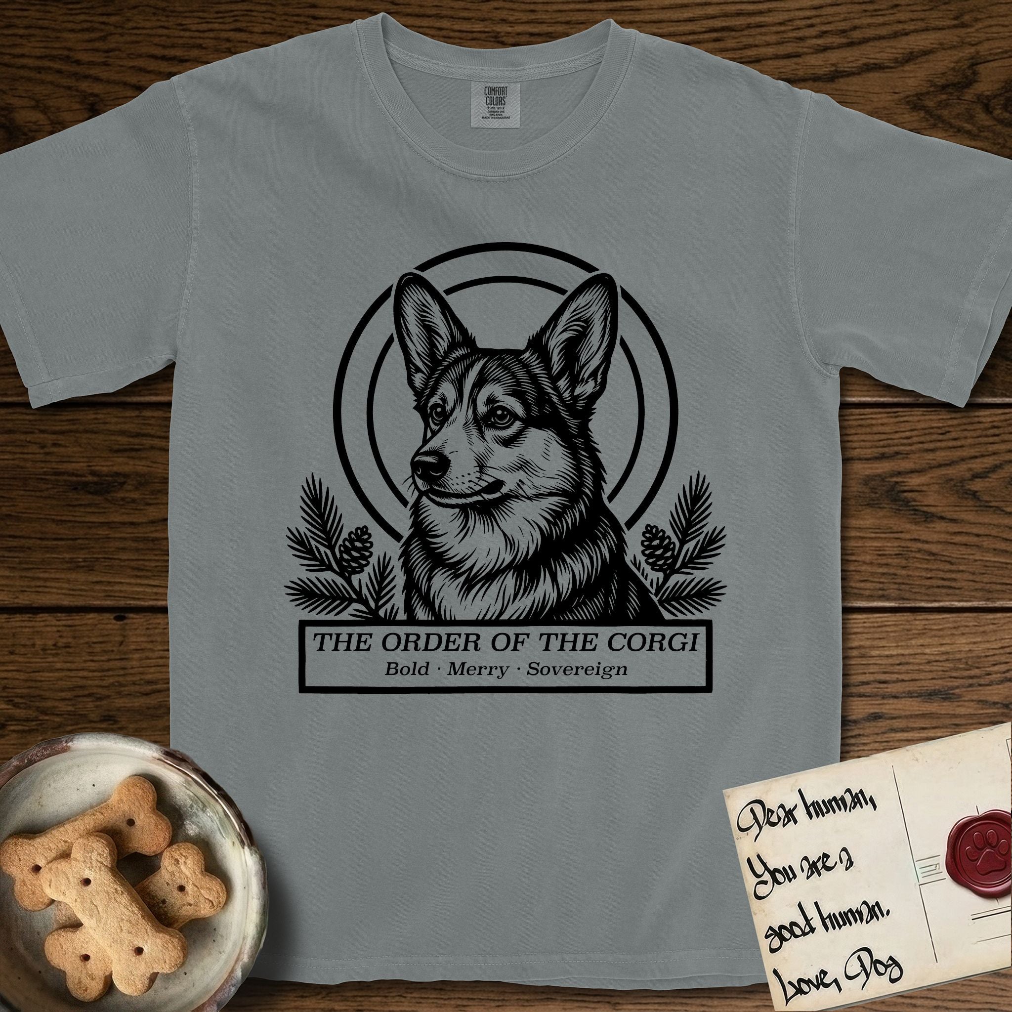 Holy Orders Corgi T-Shirt flat lay in Granite, featuring a bold black-and-white linocut saint-medallion portrait of a Corgi.