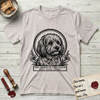 Holy Orders Coton T-Shirt flat lay in Ice Grey, featuring a bold black-and-white linocut saint-medallion portrait of a Coton de Tulear.