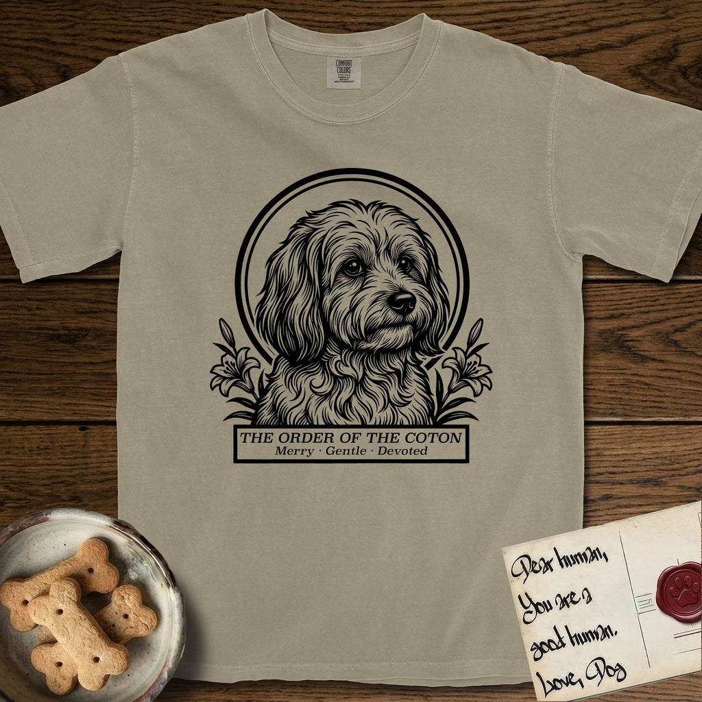 Holy Orders Coton T-Shirt flat lay in Khaki, featuring a bold black-and-white linocut saint-medallion portrait of a Coton de Tulear.