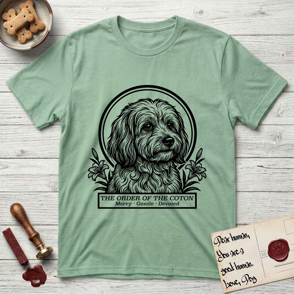 Holy Orders Coton T-Shirt flat lay in Mint Green, featuring a bold black-and-white linocut saint-medallion portrait of a Coton de Tulear.