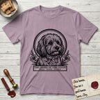 Holy Orders Coton T-Shirt flat lay in Paragon, featuring a bold black-and-white linocut saint-medallion portrait of a Coton de Tulear.