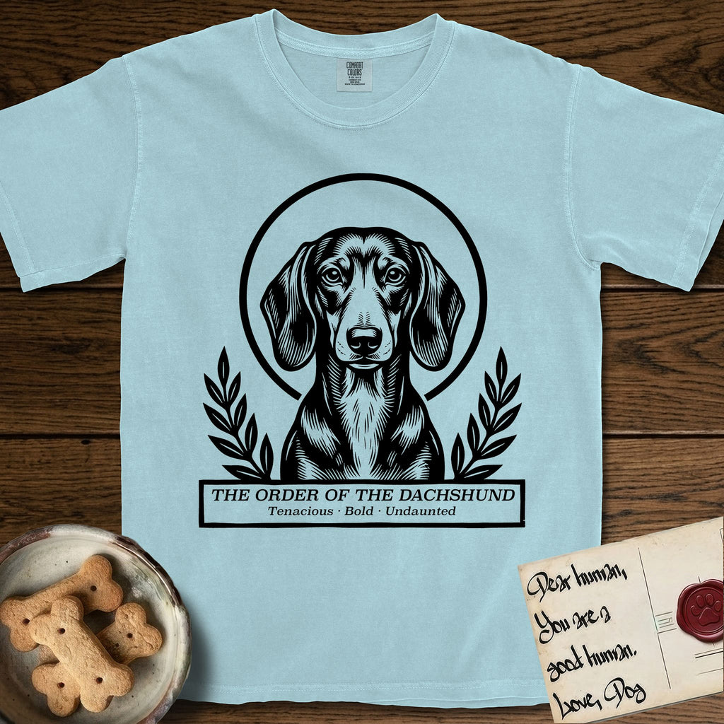 Holy Orders Dachshund T-Shirt flat lay in Chambray, featuring a bold black-and-white linocut saint-medallion portrait of a Dachshund.