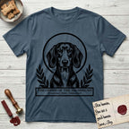Holy Orders Dachshund T-Shirt flat lay in Indigo Blue, featuring a bold black-and-white linocut saint-medallion portrait of a Dachshund.
