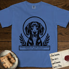 Holy Orders Dachshund T-Shirt flat lay in Mystic Blue, featuring a bold black-and-white linocut saint-medallion portrait of a Dachshund.