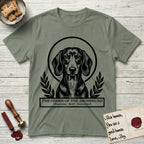Holy Orders Dachshund T-Shirt flat lay in Sage, featuring a bold black-and-white linocut saint-medallion portrait of a Dachshund.