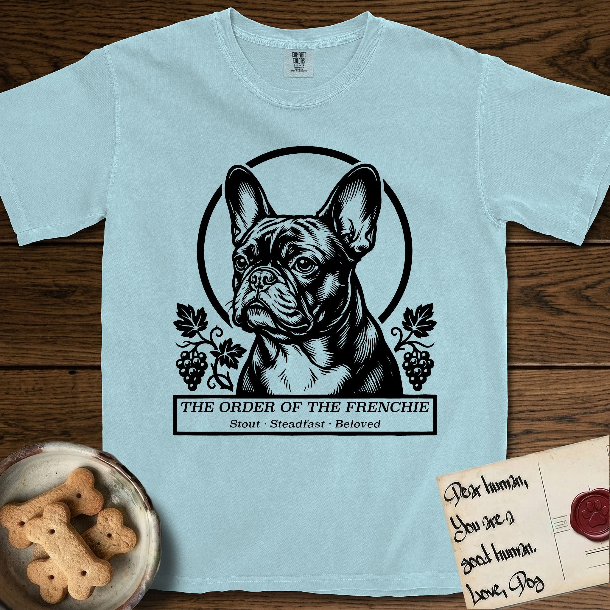Holy Orders French Bulldog T-Shirt flat lay in Chambray, featuring a bold black-and-white linocut saint-medallion portrait of a French Bulldog.