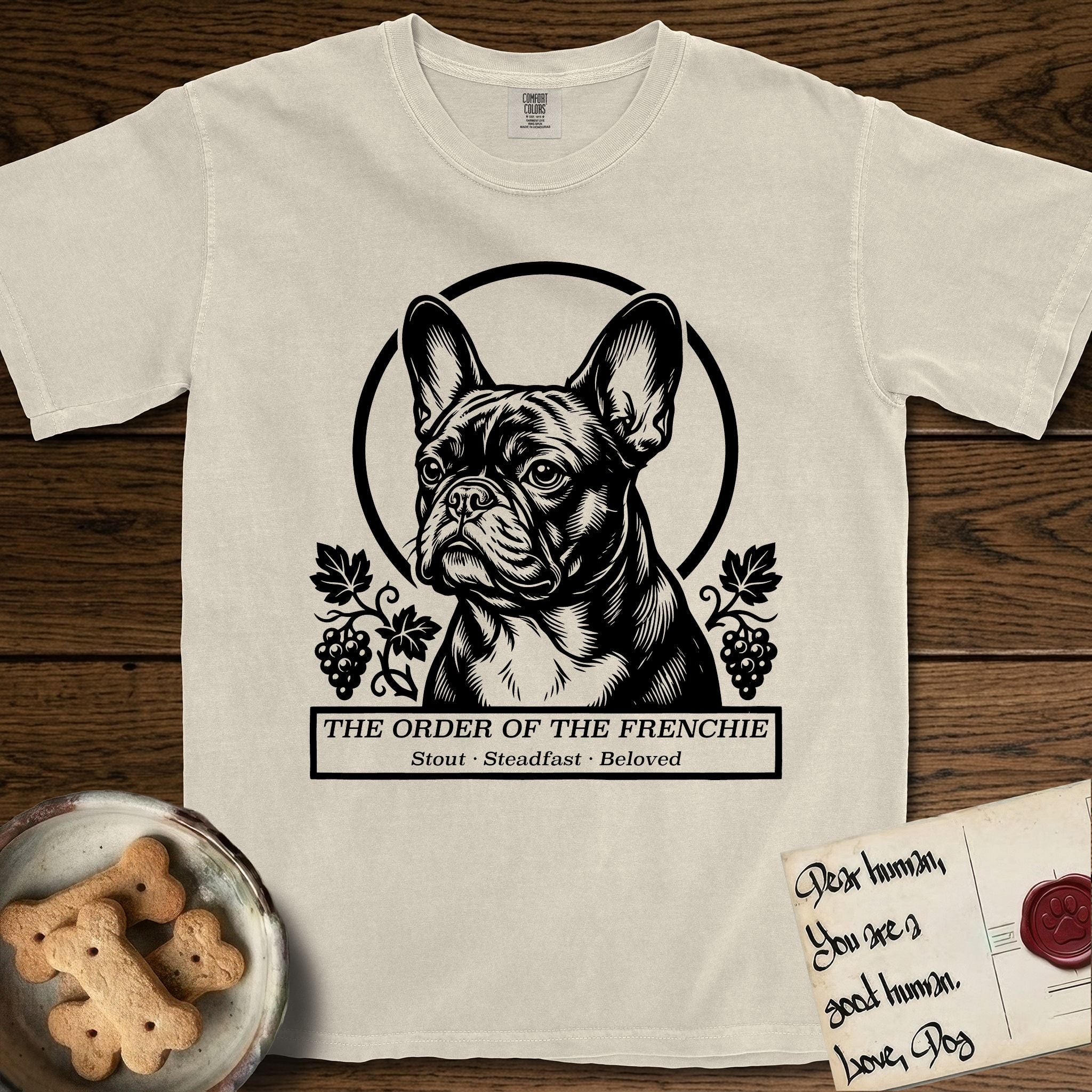 Holy Orders French Bulldog T-Shirt flat lay in Ivory, featuring a bold black-and-white linocut saint-medallion portrait of a French Bulldog.