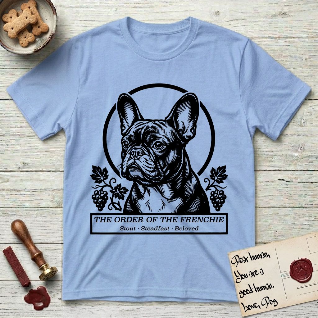 Holy Orders French Bulldog T-Shirt flat lay in Light Blue, featuring a bold black-and-white linocut saint-medallion portrait of a French Bulldog.