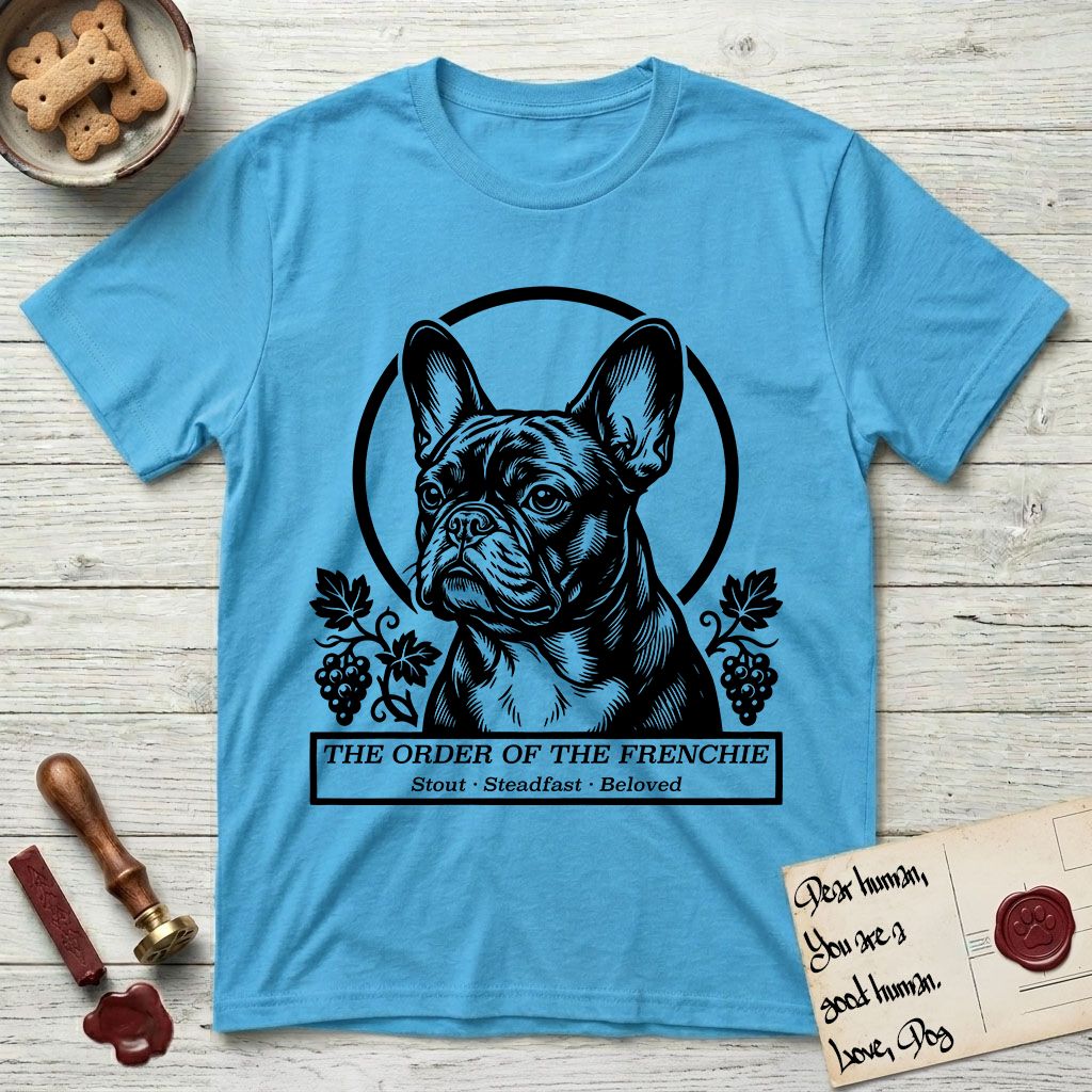 Holy Orders French Bulldog T-Shirt flat lay in Sky, featuring a bold black-and-white linocut saint-medallion portrait of a French Bulldog.
