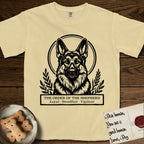 Holy Orders German Shepherd T-Shirt flat lay in Butter, featuring a bold black-and-white linocut saint-medallion portrait of a German Shepherd.
