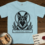 Holy Orders German Shepherd T-Shirt flat lay in Chambray, featuring a bold black-and-white linocut saint-medallion portrait of a German Shepherd.