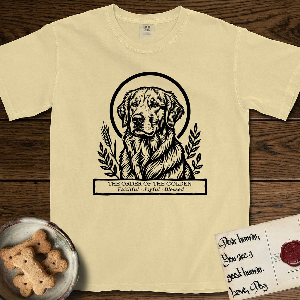 Holy Orders Golden Retriever T-Shirt flat lay in Butter, featuring a bold black-and-white linocut saint-medallion portrait of a Golden Retriever.