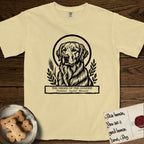 Holy Orders Golden Retriever T-Shirt flat lay in Butter, featuring a bold black-and-white linocut saint-medallion portrait of a Golden Retriever.