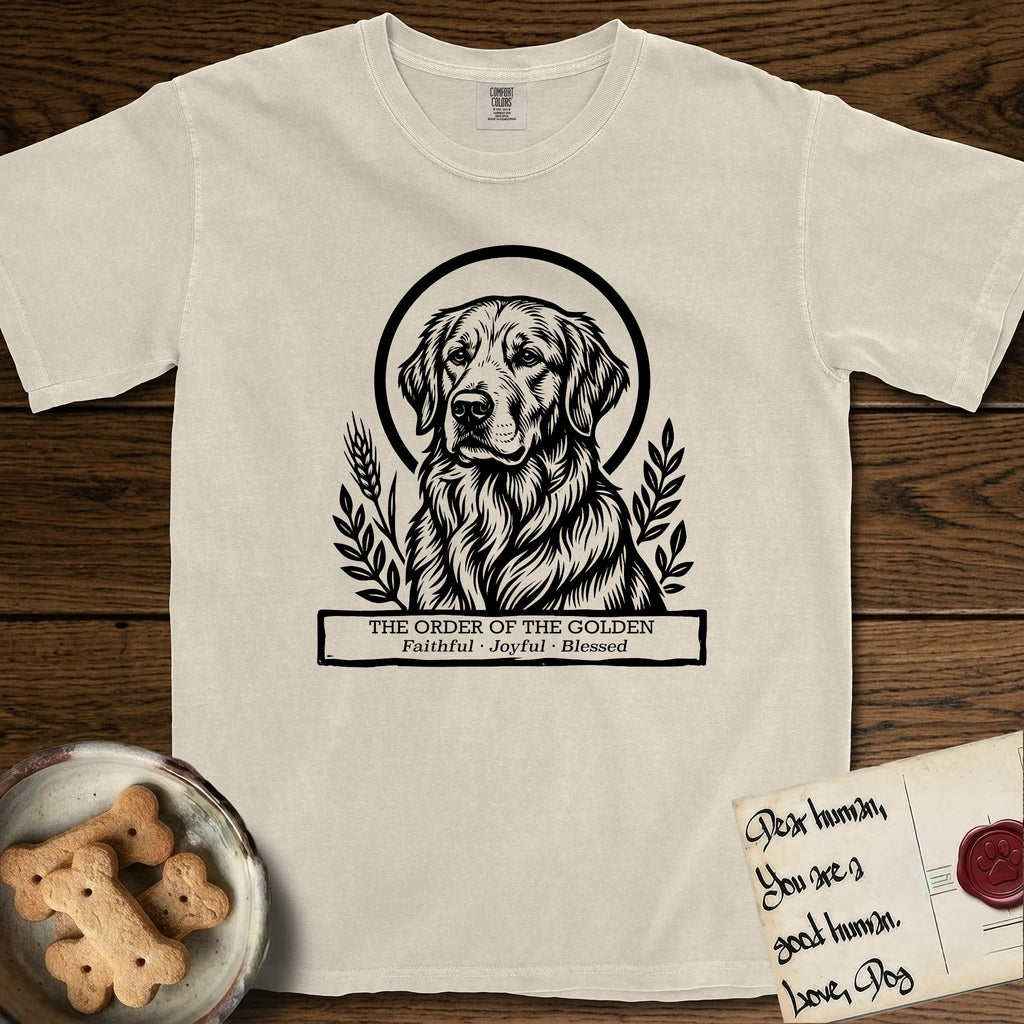 Holy Orders Golden Retriever T-Shirt flat lay in Ivory, featuring a bold black-and-white linocut saint-medallion portrait of a Golden Retriever.