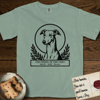 Holy Orders Greyhound T-Shirt flat lay in Bay, featuring a bold black-and-white linocut saint-medallion portrait of a Greyhound.