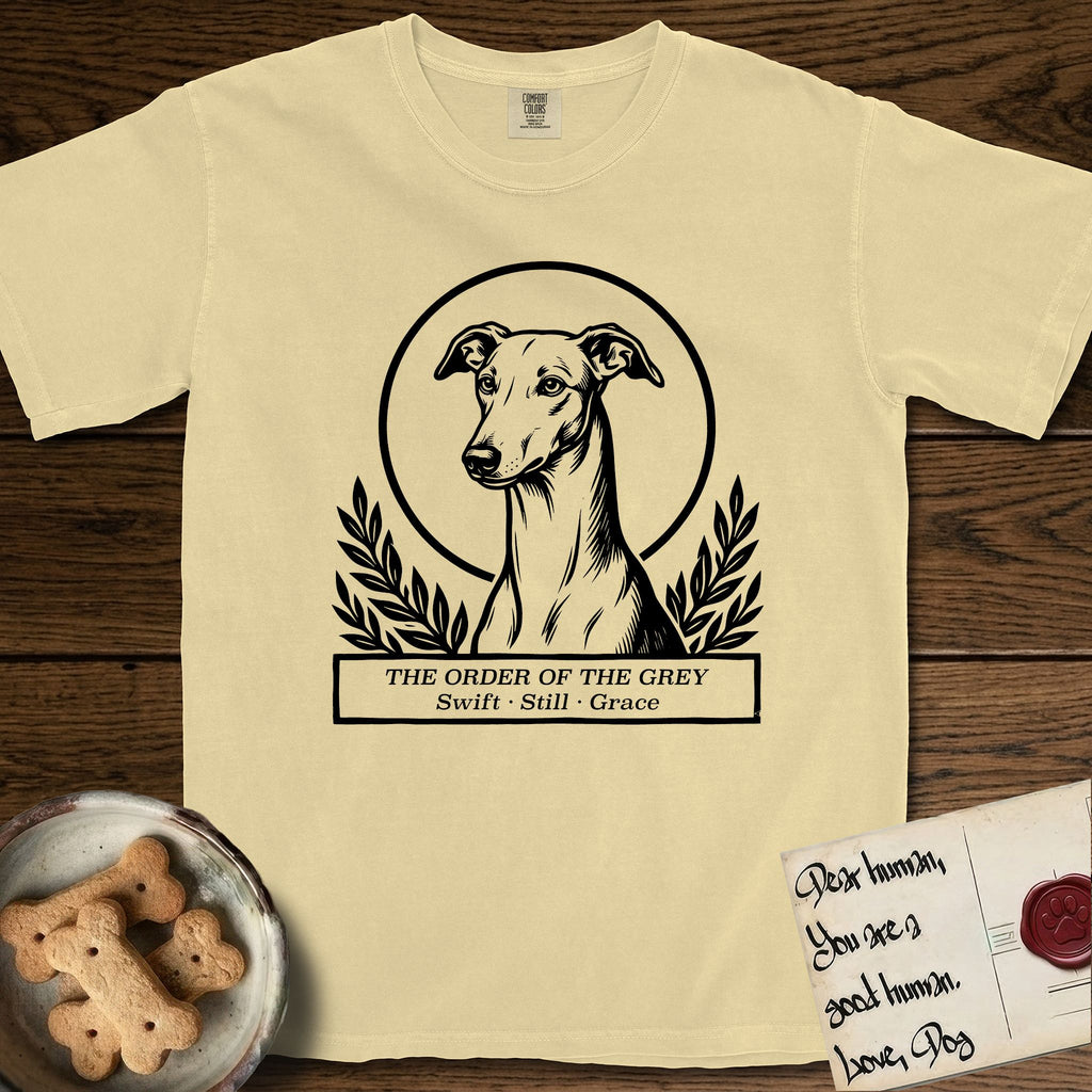 Holy Orders Greyhound T-Shirt flat lay in Butter, featuring a bold black-and-white linocut saint-medallion portrait of a Greyhound.