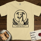 Holy Orders Greyhound T-Shirt flat lay in Butter, featuring a bold black-and-white linocut saint-medallion portrait of a Greyhound.