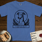 Holy Orders Greyhound T-Shirt flat lay in Mystic Blue, featuring a bold black-and-white linocut saint-medallion portrait of a Greyhound.