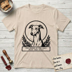 Holy Orders Greyhound T-Shirt flat lay in Sand, featuring a bold black-and-white linocut saint-medallion portrait of a Greyhound.